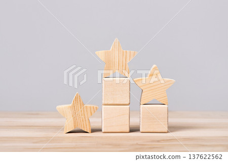 Wooden figurines of stars stand on podium as symbol of success and awards, employee performance evaluation and HR selection, selection, leadership, excellence and customer satisfaction 137622562