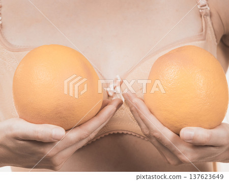 Woman small boobs holds big orange fruits Woman small boobs holds big orange fruits 137623649