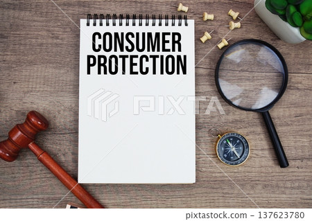 Consumer Protection message written on notepad with wood gavel and magnifying glass flat lay on wooden background 137623780