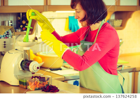 Woman make vegetables juice in juicer machine Woman make vegetables juice in juicer machine 137624258