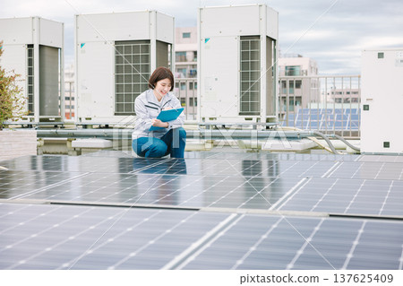 Female worker inspecting solar panels 137625409