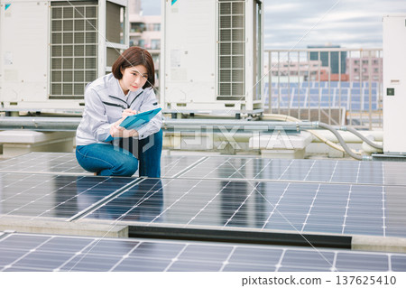 Female worker inspecting solar panels Female worker inspecting solar panels 137625410