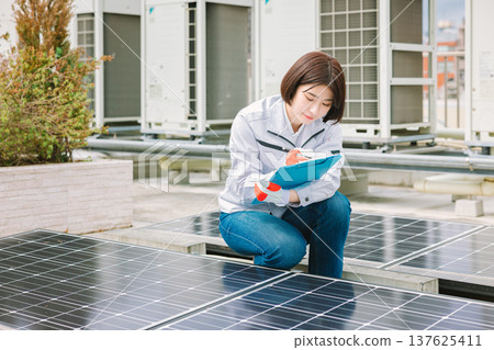 Female worker inspecting solar panels 137625411