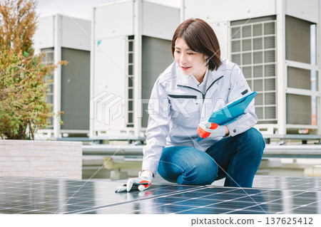 Female worker inspecting solar panels 137625412