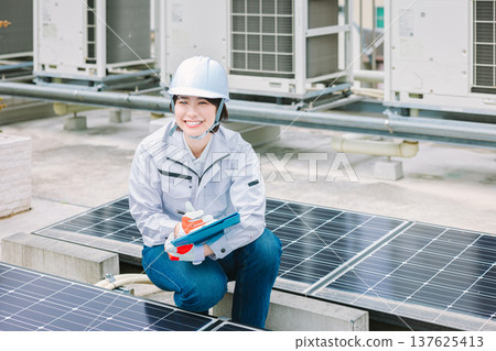 Female worker inspecting solar panels Female worker inspecting solar panels 137625413