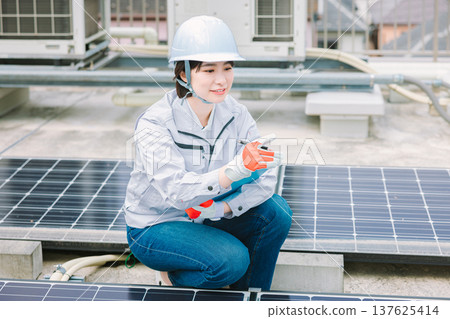 Female worker inspecting solar panels Female worker inspecting solar panels 137625414