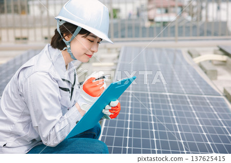 Female worker inspecting solar panels 137625415