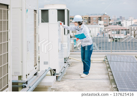 Female worker who inspects and maintains the outdoor unit 137625416
