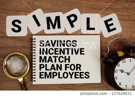 SIMPLE Savings Incentive Match Plan for Employees text on notepad with magnifying glass and alarm clock on wooden background SIMPLE Savings Incentive Match Plan for Employees text on notepad with magnifying glass and alarm clock on wooden background 137626651