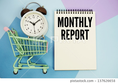 Monthly Report text written on notepad with alarm clock and trolley shopping cart 137626658