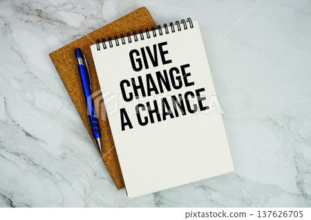 Give Change A Chance text written on notepad with pen on marble background 137626705