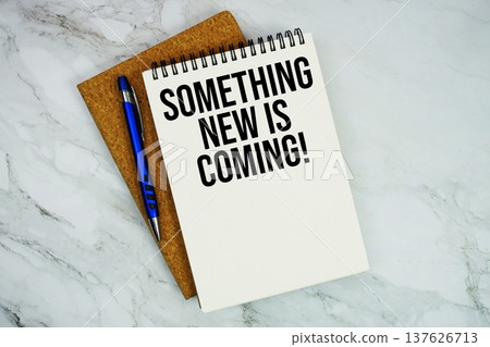 Something New Is Coming! text written on notepad with pen on marble background Something New Is Coming! text written on notepad with pen on marble background 137626713