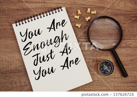 You Are Enough Just As You Are text written on notepad with compass and magnifying glass flat lay on wooden background 137626728