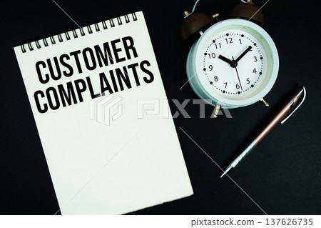 Customer Complaints text written on notepad with pen and alarm clock Customer Complaints text written on notepad with pen and alarm clock 137626735