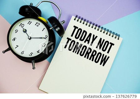 Today Not Tomorrow text written on notepad with alarm clock flat lay on multicolor pastel background Today Not Tomorrow text written on notepad with alarm clock flat lay on multicolor pastel background 137626779