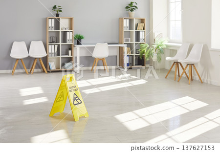 Yellow caution wet floor sign warning employees about slippery surface after recent cleaning. 137627153