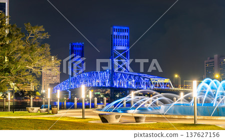 Beautiful night view of the illuminated Main Street Bridge and Friendship Fountain in downtown Jacksonville, Florida, with city lights and urban architecture. Beautiful night view of the illuminated Main Street Bridge and Friendship Fountain in downtown Jacksonville, Florida, with city lights and urban architecture. 137627156