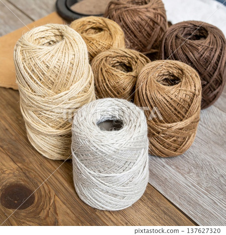 Assortment of Brown and Beige Yarn Balls on Rustic Wooden Surface with Natural Light 137627320