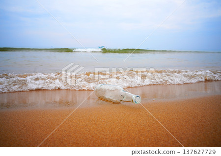 Message in bottle on sandy beach near ocean with gentle waves. Bottle appears to contain message. Message in bottle on sandy beach near ocean with gentle waves. Bottle appears to contain message. 137627729