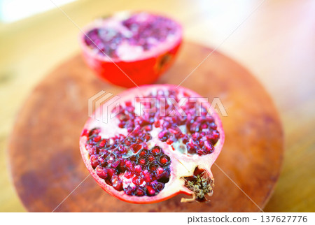 Pomegranate is cut in half on wooden surface. Fresh pomegranate cut in half showing seeds Pomegranate is cut in half on wooden surface. Fresh pomegranate cut in half showing seeds 137627776