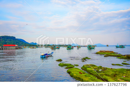 Fishing boats at shore as clouds cover sky. Fishermen boats in sea at rocky shore in fishing village Fishing boats at shore as clouds cover sky. Fishermen boats in sea at rocky shore in fishing village 137627796