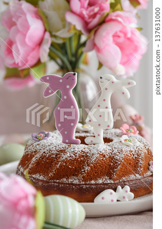 Traditional easter cakes with icing decorated with gingerbread cookies in shape of rabbits on white wooden table Traditional easter cakes with icing decorated with gingerbread cookies in shape of rabbits on white wooden table 137631000