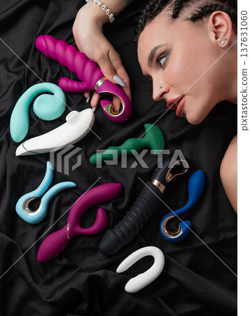 Portrait of Caucasian woman lying on bed among sex toys.  137631060
