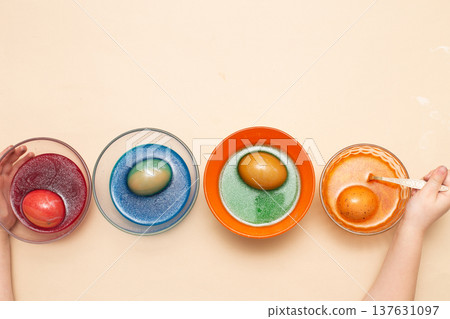 Hands of a girl child coloring festive Easter eggs with colorful dyes on the table at home Hands of a girl child coloring festive Easter eggs with colorful dyes on the table at home 137631097