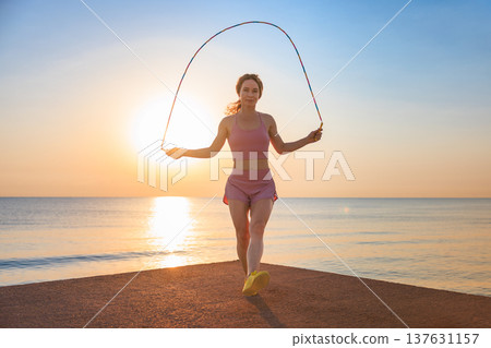Fit woman jumping rope at the beach during summer vacation Fit woman jumping rope at the beach during summer vacation 137631157