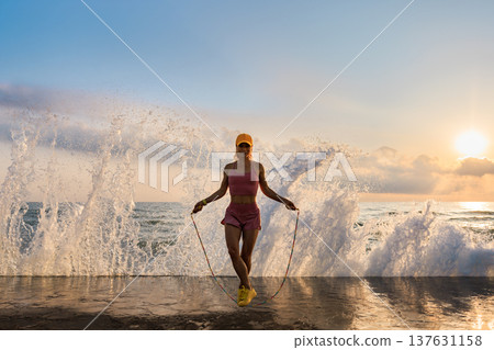 Fit woman jumping rope at the beach during summer vacation Fit woman jumping rope at the beach during summer vacation 137631158