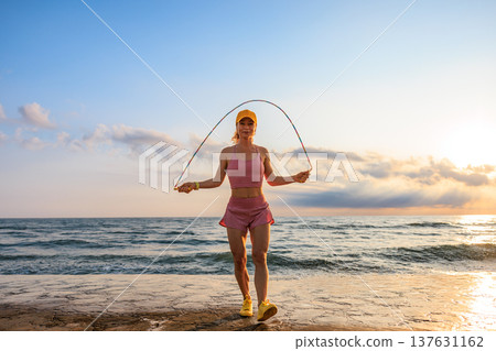 Fit woman jumping rope at the beach during summer vacation Fit woman jumping rope at the beach during summer vacation 137631162
