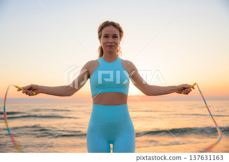 Fit woman jumping rope at the beach during vacation. Healthy lifestyle and summer sport concept Fit woman jumping rope at the beach during vacation. Healthy lifestyle and summer sport concept 137631163