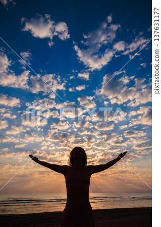 Happy woman enjoying sunrise at the beach during summer vacation Happy woman enjoying sunrise at the beach during summer vacation 137631177