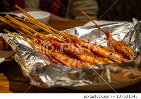 Grilled prawn skewers on foil at restaurant table 137631345