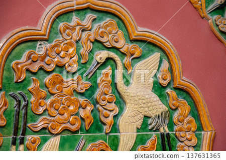 Ornate glazed tile relief of crane on traditional temple wall 137631365