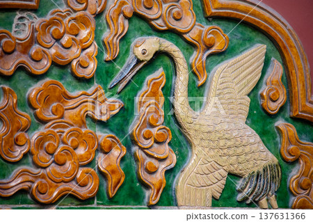 Ornate glazed tile relief of crane on traditional temple wall Ornate glazed tile relief of crane on traditional temple wall 137631366
