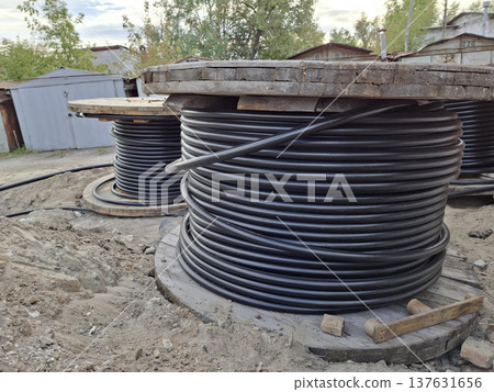 Black cables in heavy spools are laid for the power grid 137631656