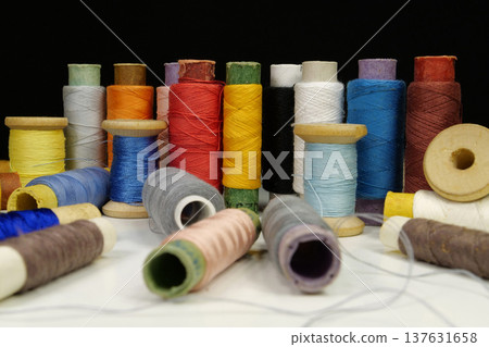 Spools with multi-colored threads on black background, close-up shot Spools with multi-colored threads on black background, close-up shot 137631658
