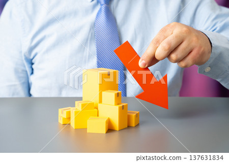 Boxes of goods and a red downward arrow. Declining imports or exports and falling sales volumes. Weak demand, market saturation and growing competition affecting trade performance. 137631834
