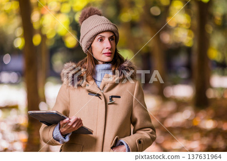 woman with eating disorders holding tablet in autumn park thinking woman with eating disorders holding tablet in autumn park thinking 137631964