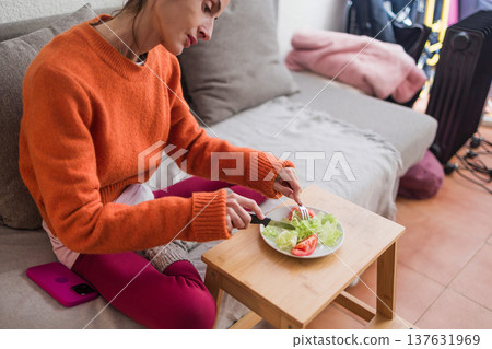 Woman struggling with eating disorder cutting small salad portion 137631969