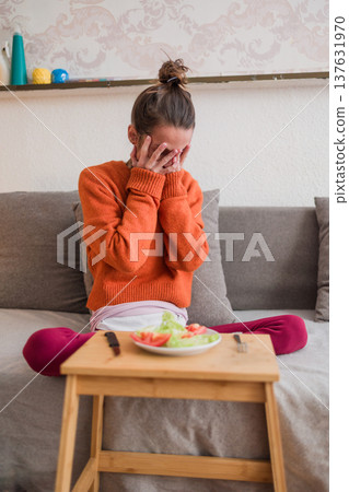 Woman grappling with eating disorder facing small food portion Woman grappling with eating disorder facing small food portion 137631970