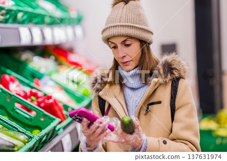 Woman counting calories on smartphone at supermarket Woman counting calories on smartphone at supermarket 137631974