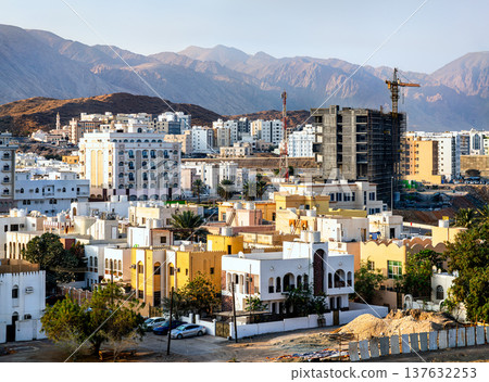 Panoramic view of the Al Khuwair district in Muscat, Oman, showing a mix of residential buildings and new construction projects against the backdrop of the rugged Hajar Mountains. Panoramic view of the Al Khuwair district in Muscat, Oman, showing a mix of residential buildings and new construction projects against the backdrop of the rugged Hajar Mountains. 137632253