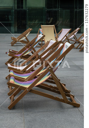 The Wooden deck chairs are arranged in a diagonal recession, creating strong leading lines that draw the eye from the foreground toward the background. The Wooden deck chairs are arranged in a diagonal recession, creating strong leading lines that draw the eye from the foreground toward the background. 137632279