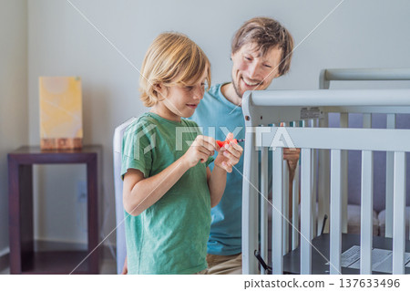 Father and older brother assembling a baby crib at home, preparing for a newborn arrival. Warm family moment full of care and anticipation. Parenthood, sibling bond and home preparation concept Father and older brother assembling a baby crib at home, preparing for a newborn arrival. Warm family moment full of care and anticipation. Parenthood, sibling bond and home preparation concept 137633496