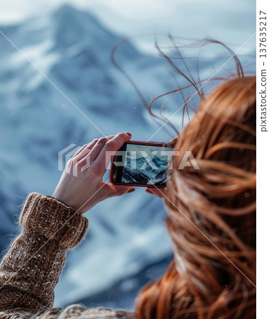 Woman Capturing Majestic Mountain Landscape with a Camera Under Bright Blue Skies and Soft, Golden Sunlight 137635217