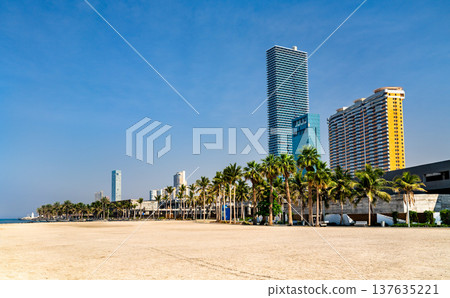 Modern skyscrapers and lush palm trees along the sandy Jeddah waterfront under a clear blue sky in Saudi Arabia Modern skyscrapers and lush palm trees along the sandy Jeddah waterfront under a clear blue sky in Saudi Arabia 137635221