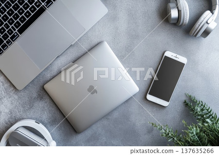 Modern workspace featuring a laptop, headphones, and a smartphone arranged neatly on a wooden table. 137635266