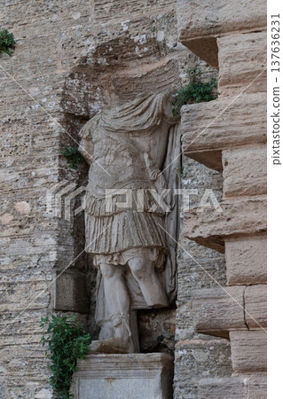 Weathered headless stone statue set in the wall at a historic castle entrance in Ibiza Spain 137636231